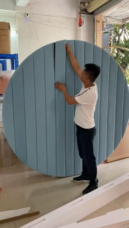 a man standing next to a giant surfboard in a room filled with cardboard boxes