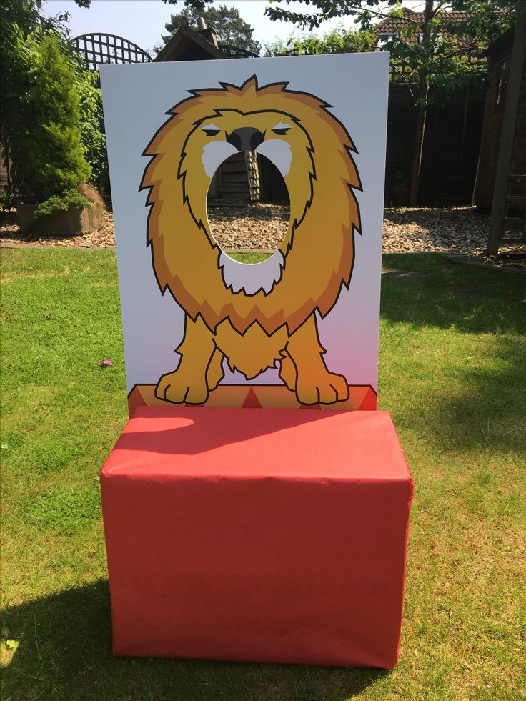 a cardboard cut out of a lion on top of a red box in the grass