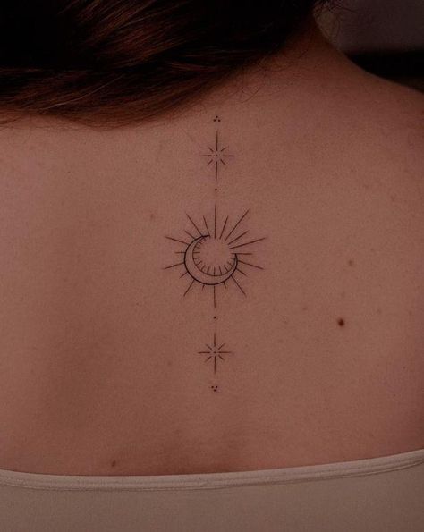 the back of a woman's neck with a sun and stars tattoo on it