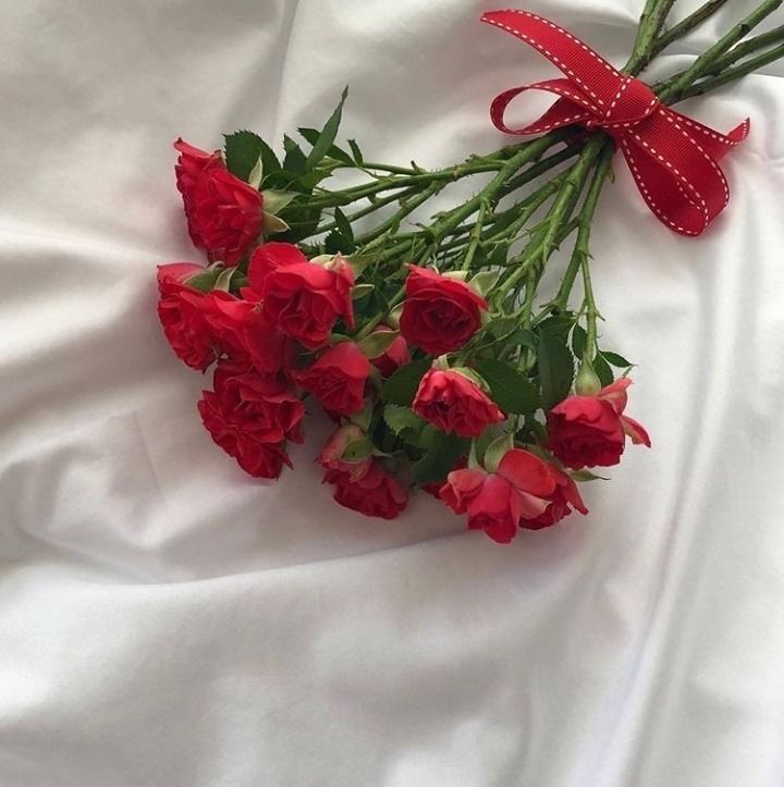 a bouquet of red roses on a white sheet