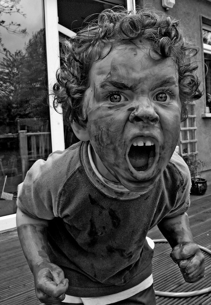 a black and white photo of a toddler with his mouth wide open, covered in blood