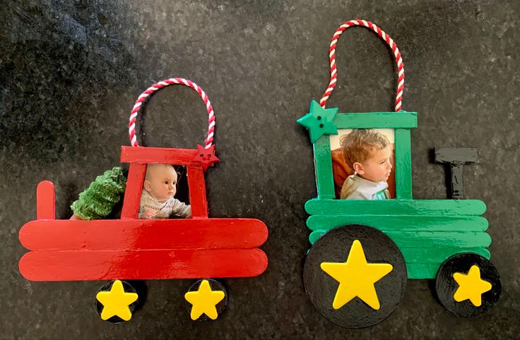 two christmas ornaments made out of popsicle sticks, one with a baby's head and the other with a toy tractor