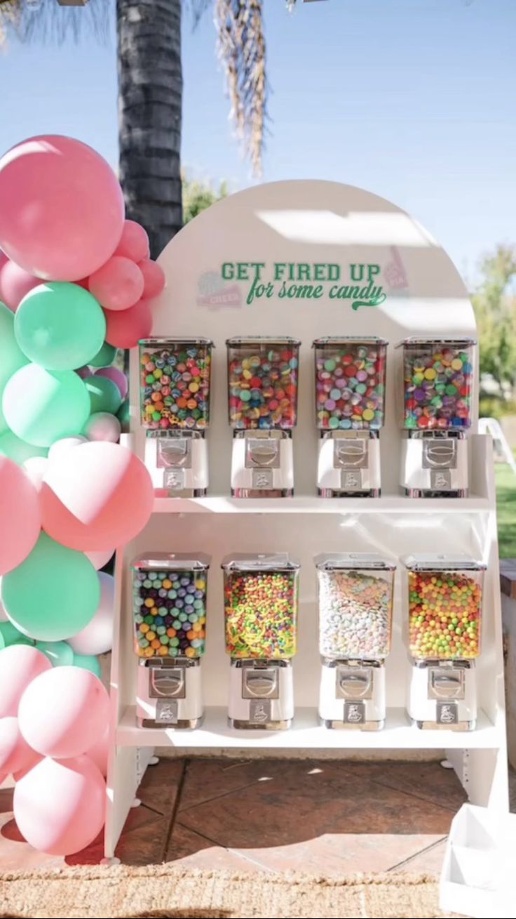 a gummy machine is set up with balloons and streamers on the front wall