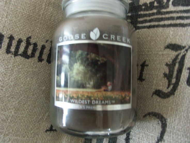 a close up of a jar of candles on a rug with the words goose creek in it