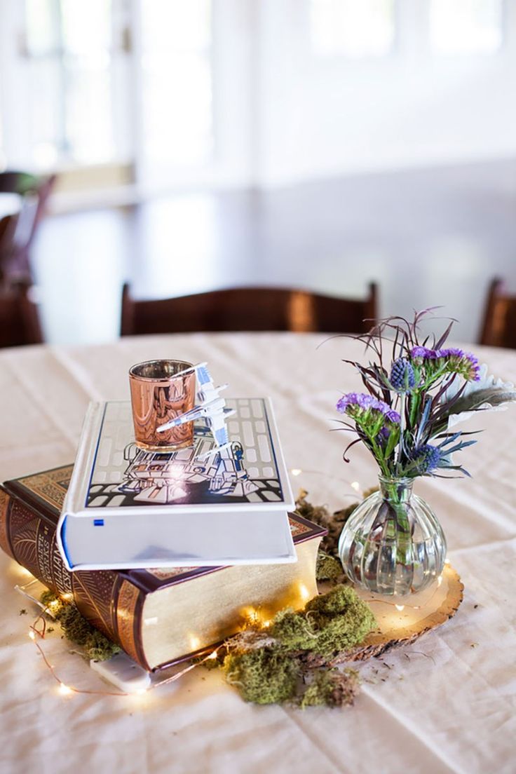 an open book sitting on top of a table next to a vase filled with flowers