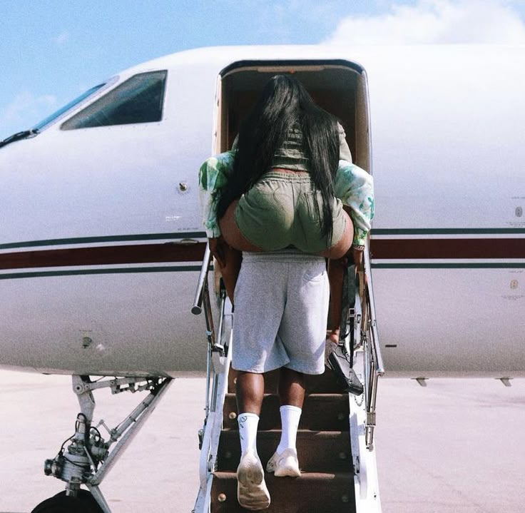 a woman walking up the stairs to an airplane with her back turned towards the camera