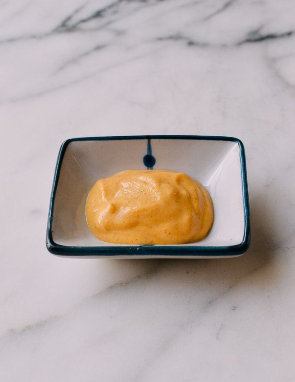 a small square bowl filled with food on top of a marble countertop next to a toothbrush