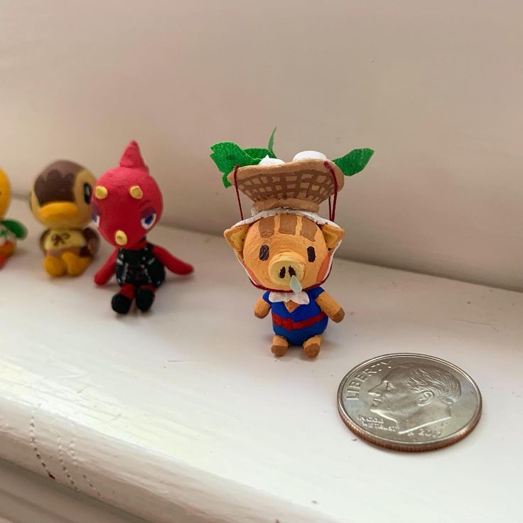 small toy figurines sitting on top of a white shelf next to a penny