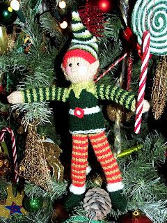 a knitted christmas ornament hanging from a tree with candy canes and candies