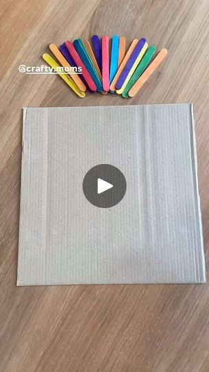 an open box with colored pencils in it on a wooden floor next to a pile of crayons