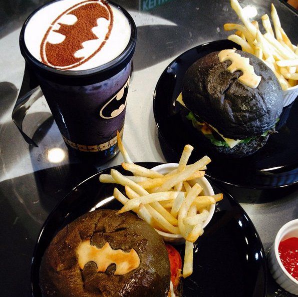 two black plates topped with burgers and fries next to cups of ketchup