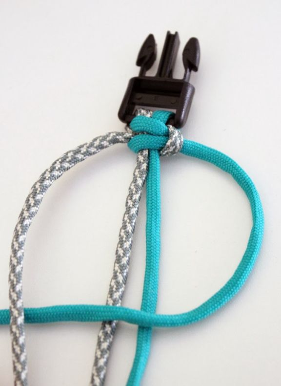 a close up of a blue and white rope attached to a black plastic object on a white surface