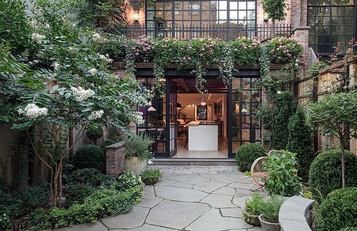 an outdoor courtyard with potted plants and greenery on the walls, surrounded by stone walkways