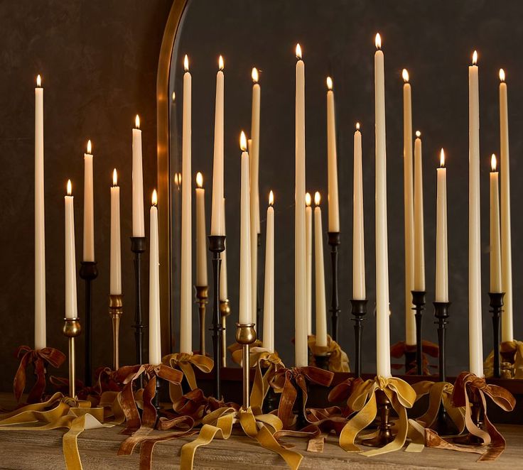 a bunch of candles that are sitting on a table with ribbons around them and bows