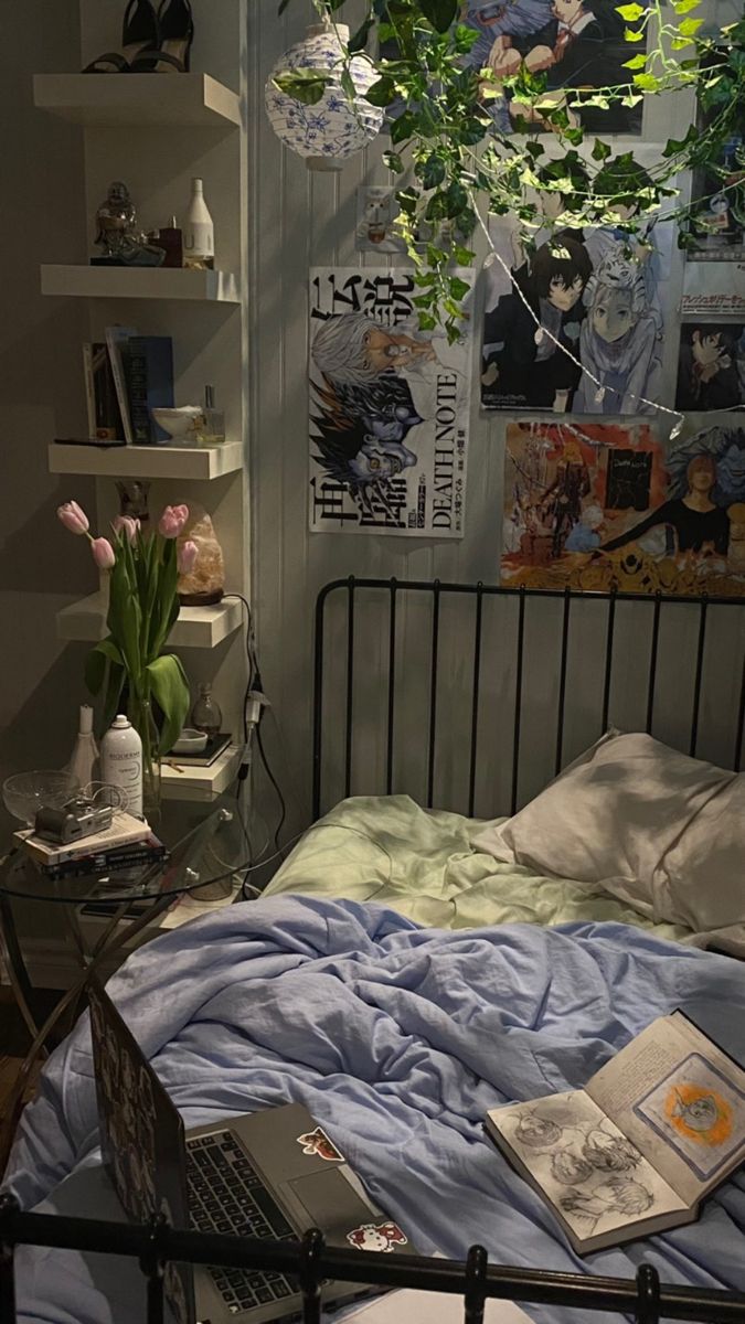 a bed with a laptop on top of it next to a book shelf filled with books