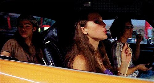 two women sitting in the back seat of a car and one woman is holding her hand up to her mouth