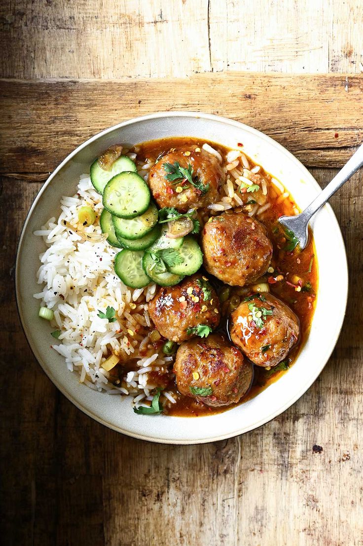 a bowl filled with meatballs, rice and cucumbers