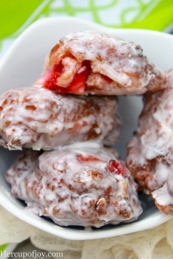 a white bowl filled with donuts covered in icing and strawberries on top of a table