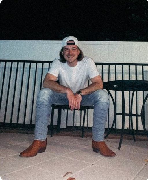 a man sitting on top of a wooden bench next to a black metal table and chair