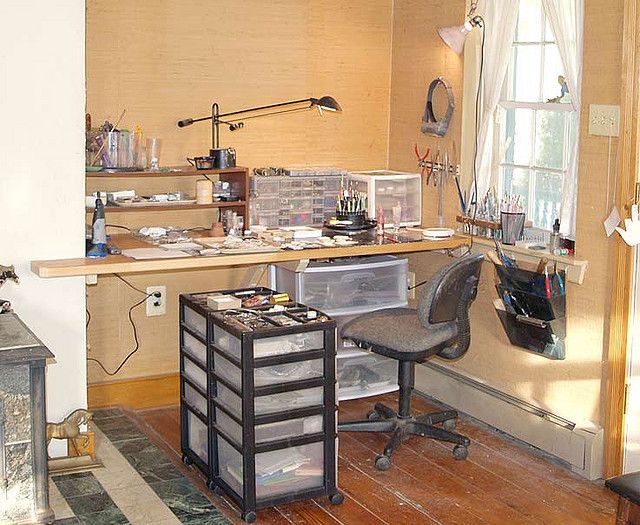 a room with a desk, chair and shelves filled with various items on the wall