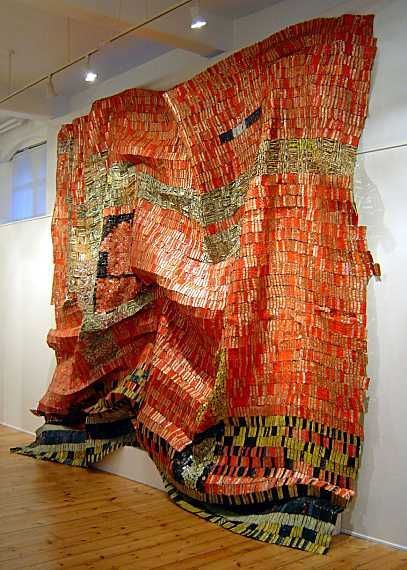 a large piece of art made out of orange and black material on a wooden floor