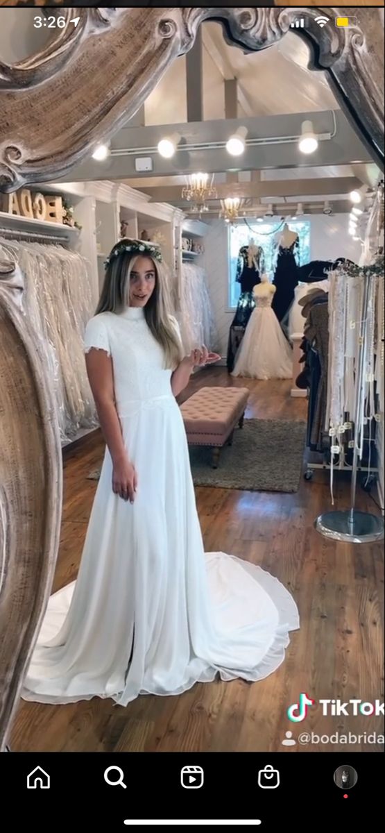 a woman standing in front of a mirror wearing a white dress