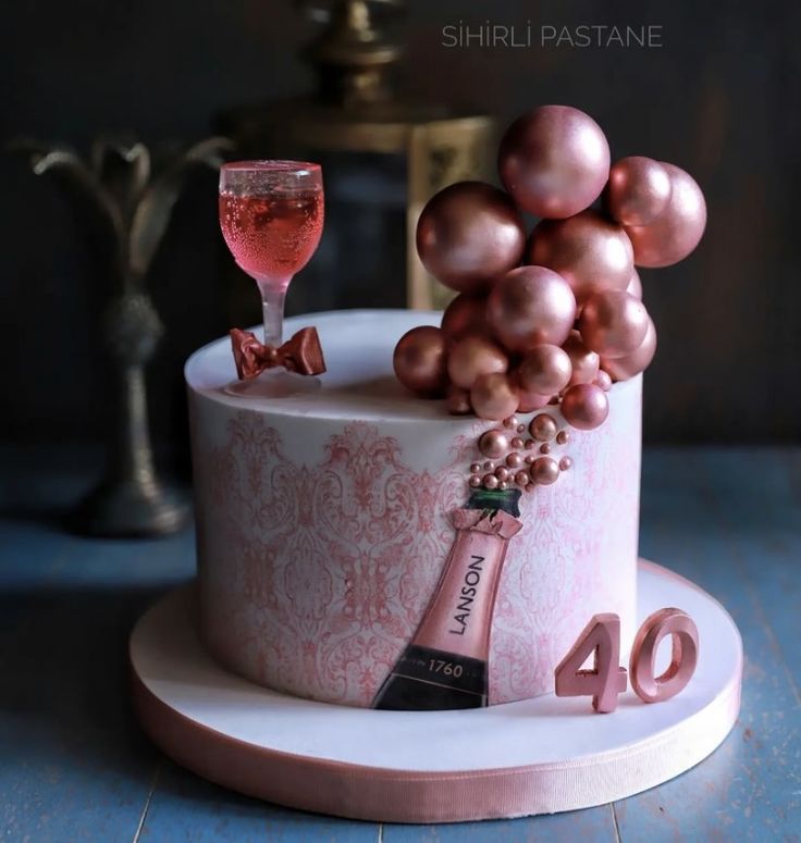 a birthday cake with a bottle of wine and some ornaments on top, sitting on a table