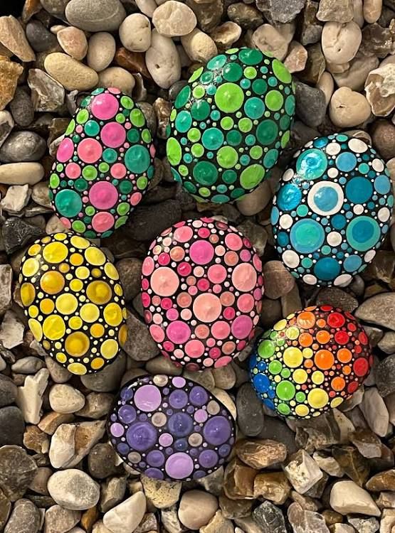 four painted rocks sitting on top of a pile of rocks next to some gravel and stones