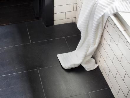 there is a white towel on the floor next to a black and white tiled wall