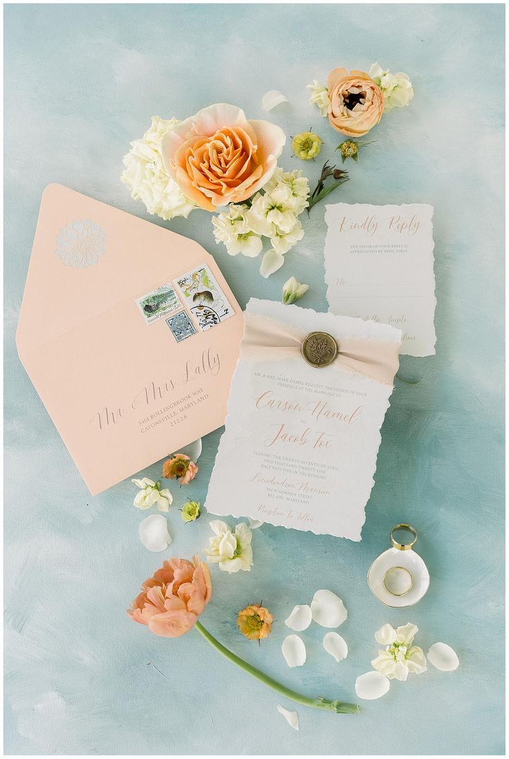 the wedding stationery is laid out on top of the blue tablecloth with flowers