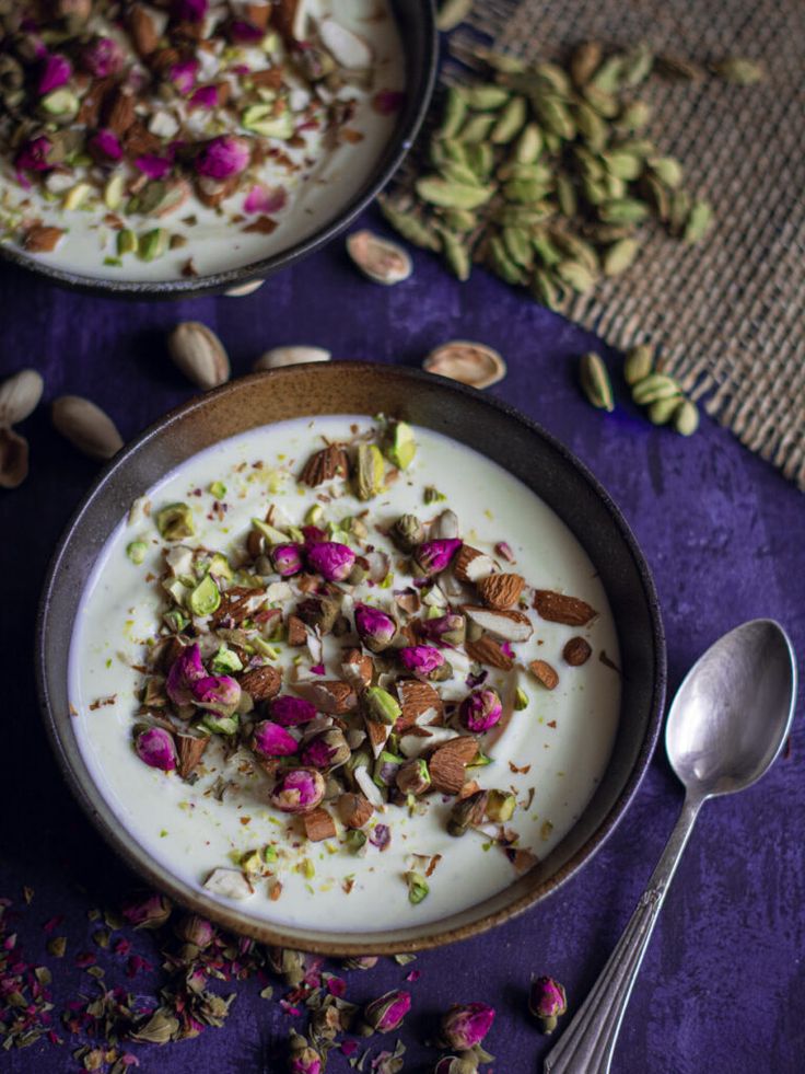 two bowls filled with yogurt and nuts on top of a purple table cloth