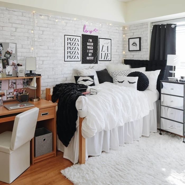 a bedroom with white brick walls, black and white decor and lots of stuff on the bed