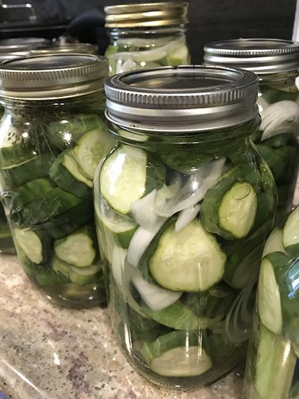 several mason jars filled with cucumbers and onions on a counter top in a kitchen