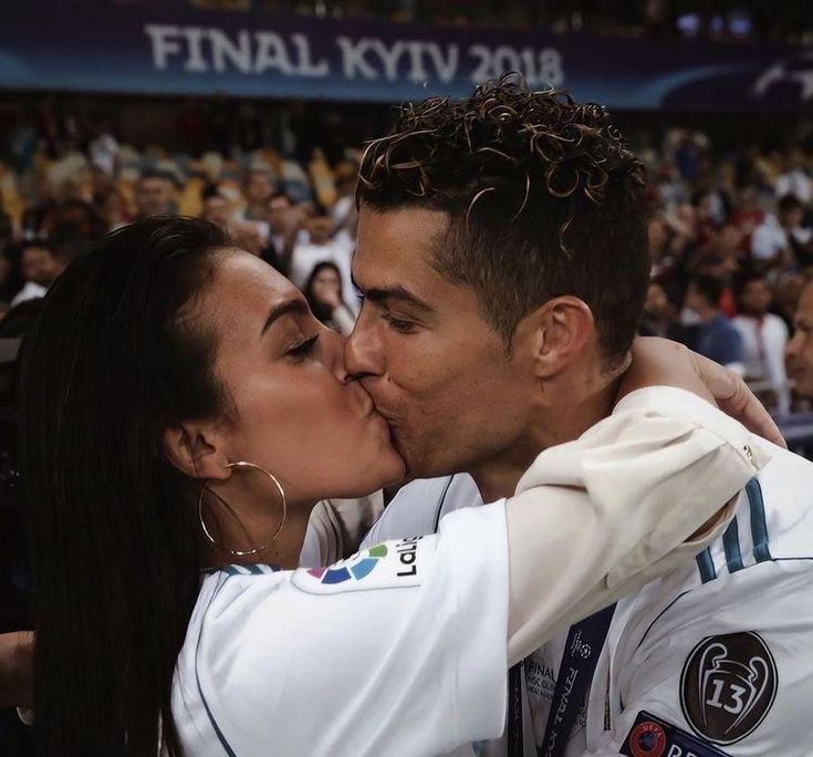 a man and woman kissing each other in front of a crowd at a sporting event