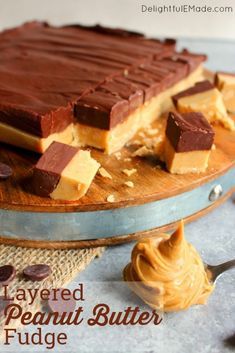 layered peanut butter fudge cake on a wooden platter with chocolate and peanut butter