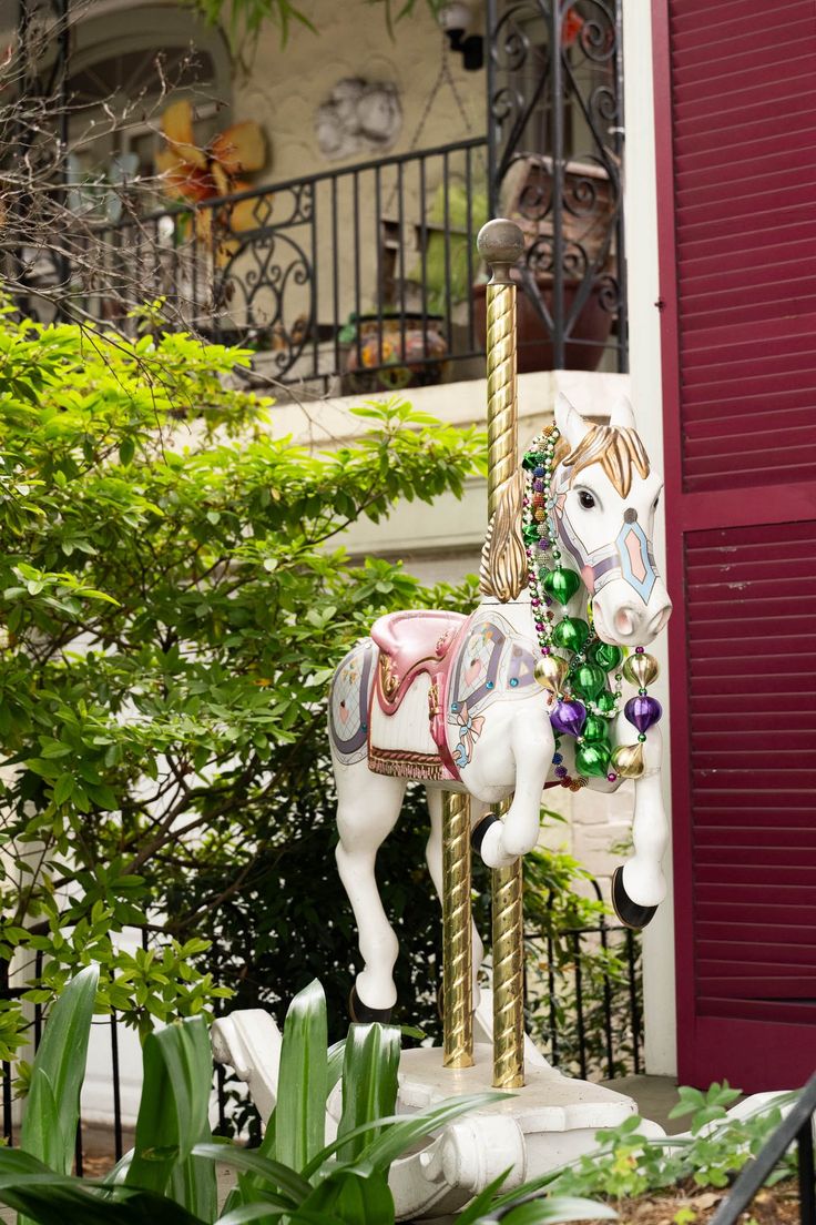 a merry go round horse on display in front of a building with red shutters