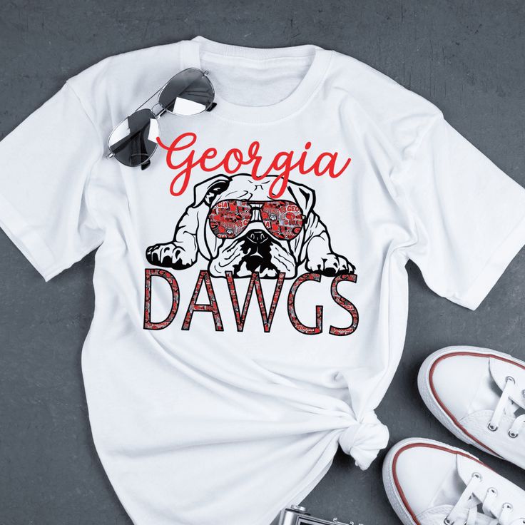 Show your school spirit in this Athens Bulldogs Tee! With its soft fabric and 100% cotton construction, it'll provide total comfort. Plus, it's got the Georgia Bulldogs logo on it, so you can proudly display your fan allegiance. Go Dawgs! Football Season Cotton Fan Apparel With Sublimation Design, Cotton Sublimation Design Fan Apparel For Football Season, School Spirit T-shirt For Fan Gear, Varsity Relaxed Fit T-shirt For Fan Gear, Cotton Sublimation T-shirt For Sports Fans, Cotton Sublimation Design T-shirt For Sports Fans, Cotton Sublimation Design For Sports Fans, Football Season Cotton Sublimation Design With Team Name, Collegiate White T-shirt With Heat Transfer Vinyl