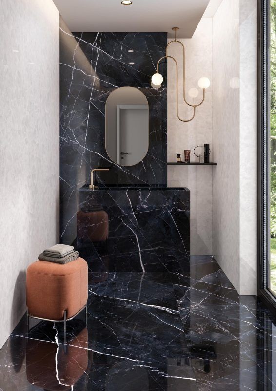 a bathroom with black marble floors and walls, along with an orange footstool