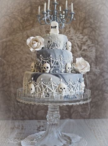 a three tiered cake with skulls and roses on the top is surrounded by candles