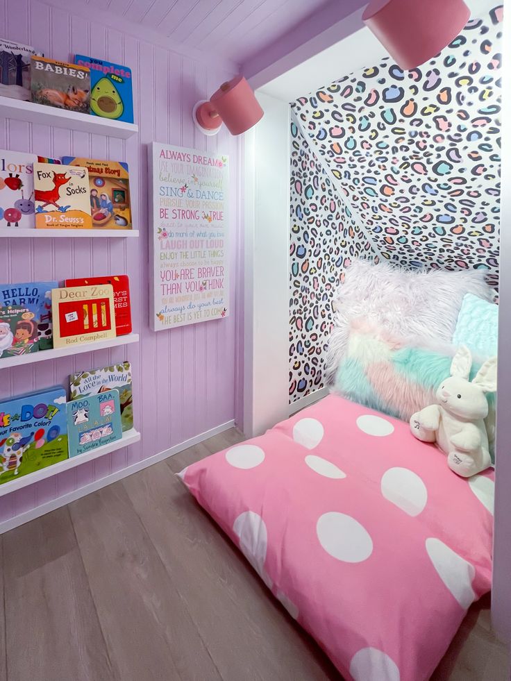 a child's bedroom decorated in pink, white and blue with bookshelves