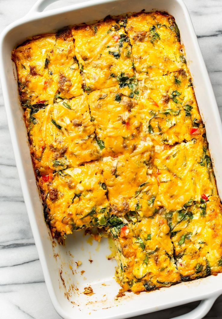 a casserole with cheese and vegetables in a white dish on a marble surface