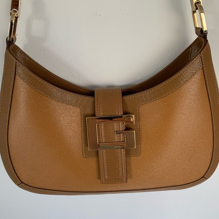 Gucci 2-Tone Tan Leather Handbag With Eye-Catching Gold-Tone Signature “G” Symbol. Size: Width: About 9 Inches At Top About 11 Inches At Bottom Length: About 6 Inches At Middle About 7 Inches At Sides Base: About 1 1/4 Inches Buckle: About 2 1/4 X 1 1/2 Inches Interior: Gucci Signature Fabric Lining - Zipper Pocket Strap: About 11 1/2-Inch Drop Made In Italy Excellent Condition - Never Used Gucci Dust Cover Gucci Shoulder Bag With Gold-tone Hardware For Shopping, Chic Gucci Shoulder Bag For Shopping, Gucci Bags With Metal Hardware For Work, Gucci Leather Shoulder Bag With Gold-tone Hardware, Everyday Gucci Shoulder Bag With Gold-tone Hardware, Gucci Satchel Shoulder Bag In Textured Leather, Gucci Textured Leather Satchel Shoulder Bag, Gucci Textured Leather Shoulder Bag, Classic Gucci Textured Leather Shoulder Bag