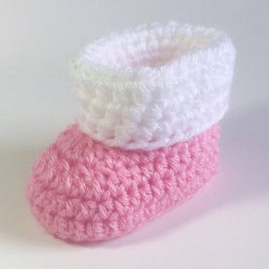 two crocheted pink and white baby booties sitting on top of each other