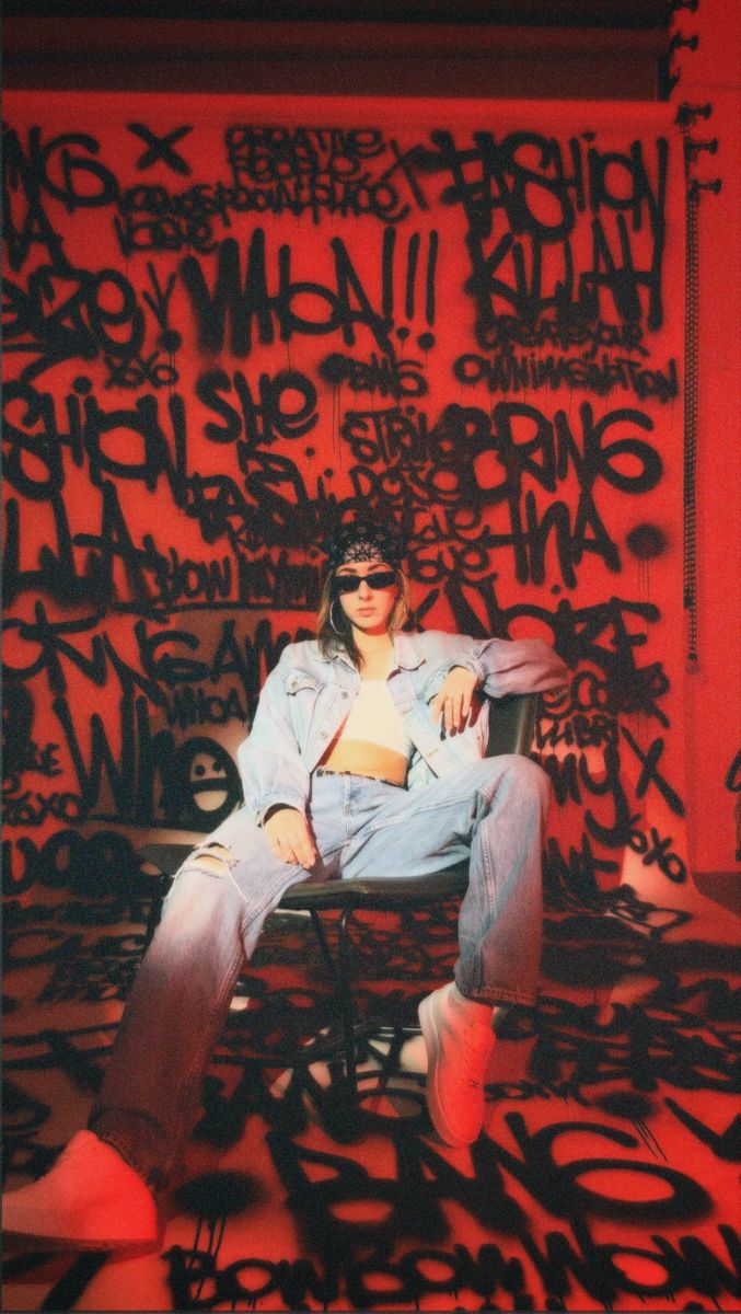 a woman sitting on top of a chair in front of graffiti