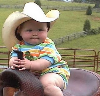 a baby wearing a cowboy hat sitting on top of a horse