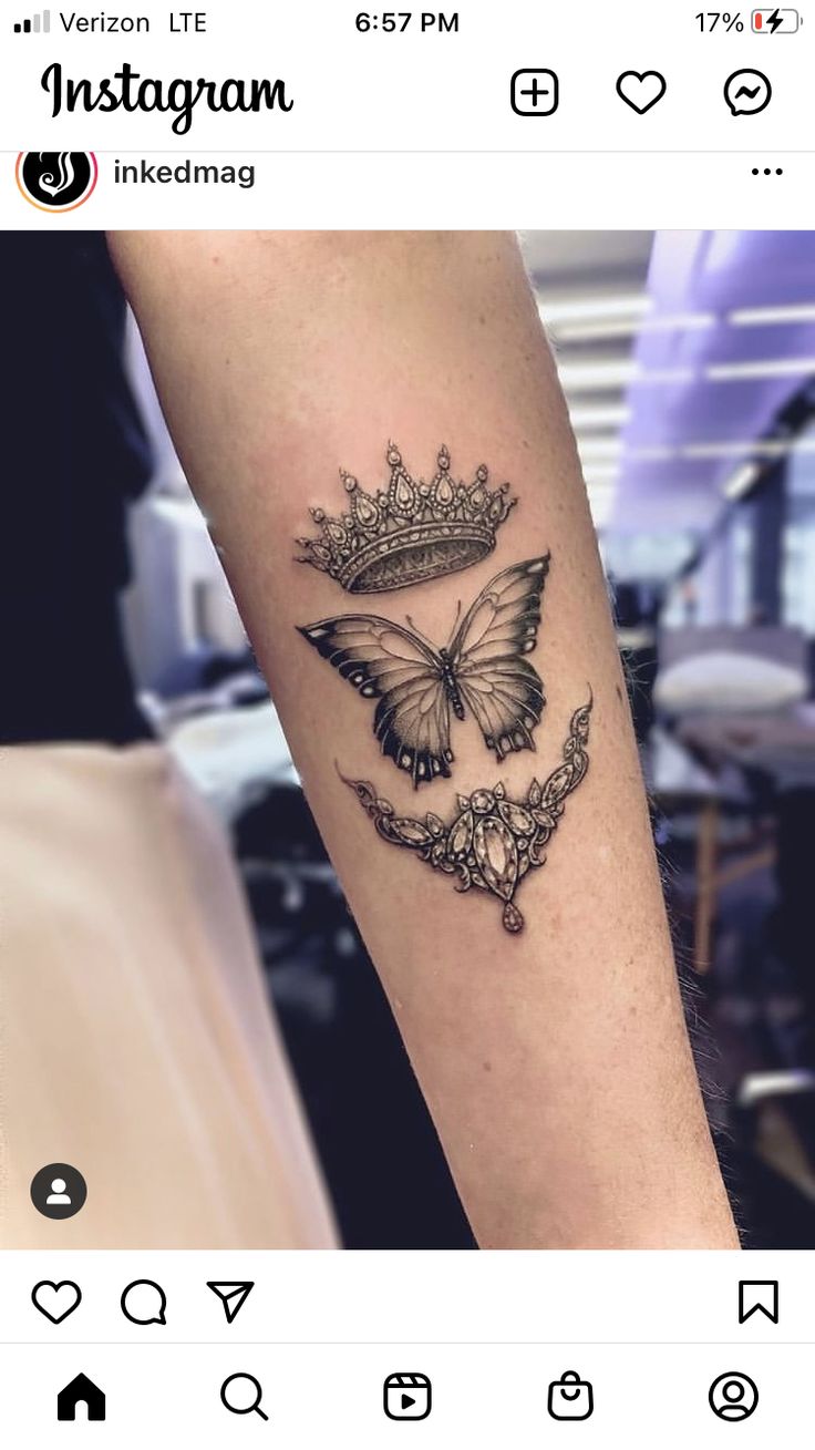 a woman's arm with a butterfly and crown tattoo on it