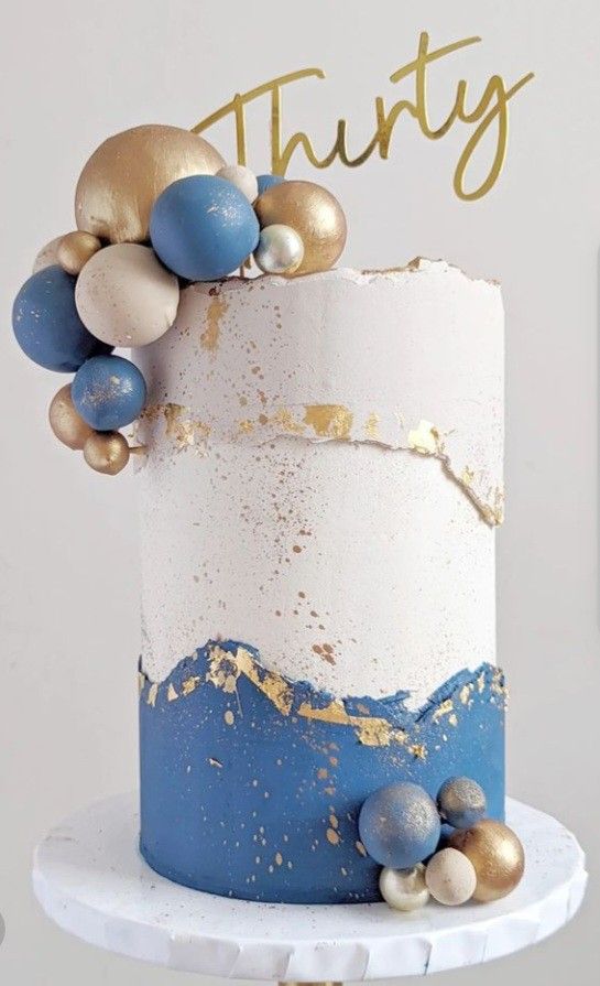 there is a white and blue cake with gold decorations on the top that says thirty