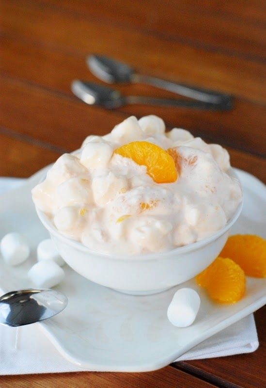 a white bowl filled with oranges on top of a plate next to silverware