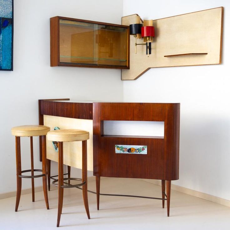 two wooden stools sitting next to each other in front of a wall mounted art piece