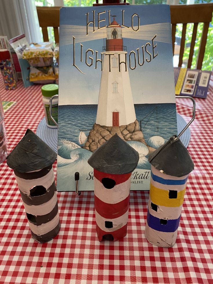 there are three lighthouses on the table with a sign in front of them that says hello lighthouse